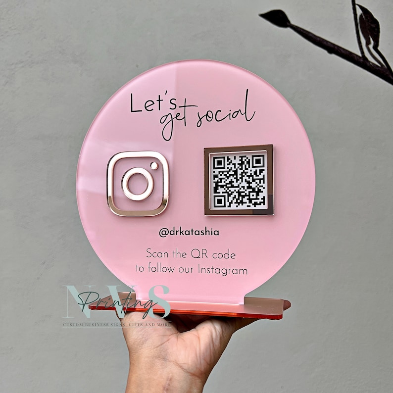 QR Code social media display stand in dusty pink acrylic backing, lets get social on top and instagram logo on the left in rose gold mirror acrylic and instagram QR code, instagram handle under the QR code and scan the QR code to follow our instagram
