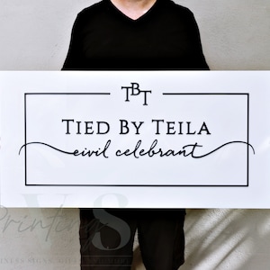Custom Rectangle acrylic business sign in gloss white backing, with 3D black acrylic logo, TBT in serif font on top, black rectangle frame, TIED BY TEILA inside the frame in serif font, CIVIL CELEBRANT in cursive font