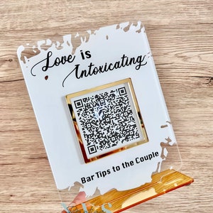 Acrylic bar tip sign, white splash background, love is intoxicating on top, QR code under it with gold mirror frame, bar tip to the couple wording under QR code and gold mirror base for free standing