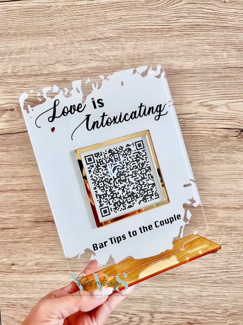 Acrylic bar tip sign, white splash background, love is intoxicating on top, QR code under it with gold mirror frame, bar tip to the couple wording under QR code and gold mirror base for free standing