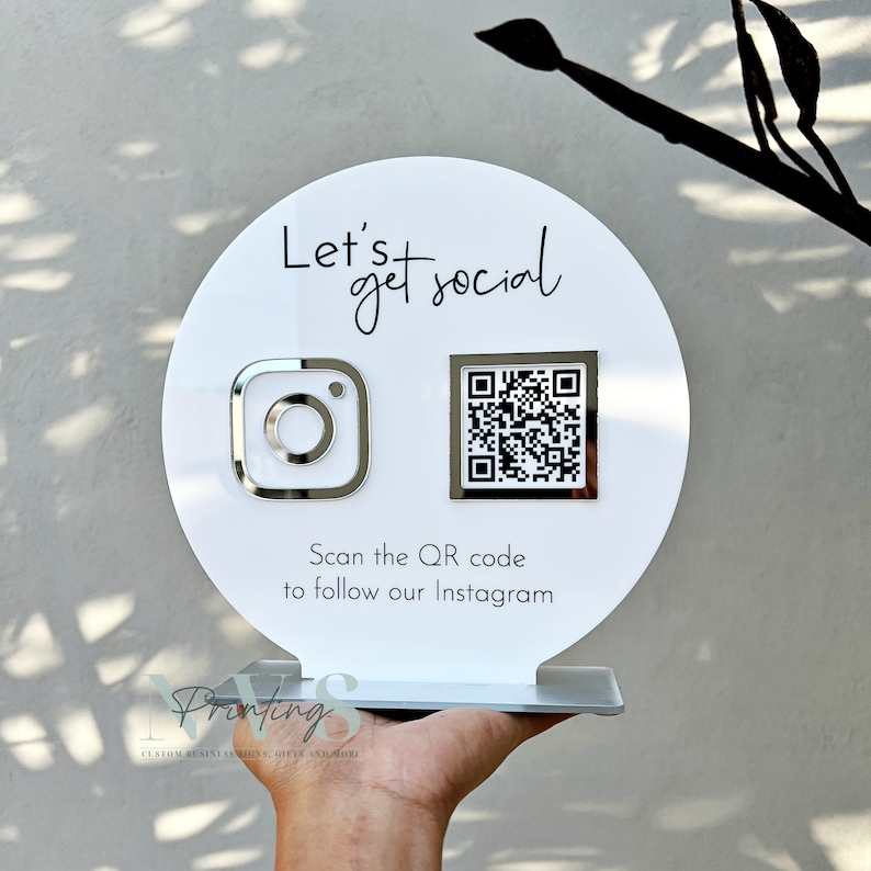 QR Code social media display stand in white acrylic backing, lets get social on top and instagram logo on the left in rsilver mirror acrylic and instagram QR code, instagram handle under the QR code and scan the QR code to follow our instagram