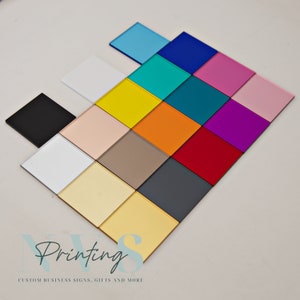May include: An assortment of square acrylic tiles in a range of colours, such as black, white, yellow, orange, and pink. The tiles are arranged in a diamond formation. The image also features the text "Printing" and "CUSTOM BUSINESS SIGNS, GIFTS AND MORE".