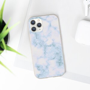 May include: A white phone case with a blue and white marble pattern. The case has a camera lens cutout.