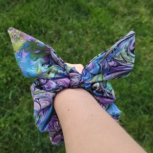 May include: A purple, blue, and green patterned hair scrunchie tied in a bow.