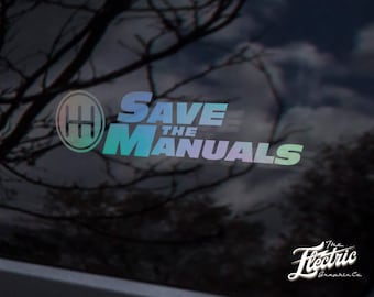 Könnte beinhalten: Ein Aufkleber mit einem Regenbogen-Farbverlauf, auf dem "SAVE THE MANUALS" mit einem Schaltmuster-Symbol steht. Der Aufkleber befindet sich auf einer schwarzen Autoscheibe. Der Text "The Electric Graphic Co." ist in Weiß unter dem Aufkleber.