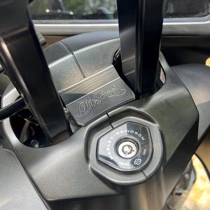 May include: Close-up of a motorcycle's handlebar area, featuring a matte gray finish. The ignition area displays the Harley-Davidson logo and the text "Old School". The handlebars are black.