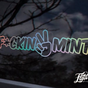 Puede incluir: Una pegatina de vinilo de colores arcoíris con el texto "F*CKIN' MINT" y un signo de paz en el medio.