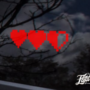 May include: Red pixelated heart graphic with three hearts, two full and one half full, on a black background. The graphic is a sticker with the text "The Electric Graphic Co." in white on a black background.