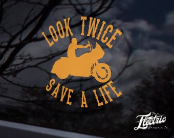 May include: Orange vinyl decal with a motorcycle silhouette and the text "Look Twice Save A Life".