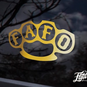 May include: Gold-colored metal knuckle duster with the letters "FAFO" embossed on each knuckle. The knuckle duster is a popular symbol of strength and power.