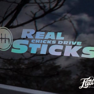 Könnte beinhalten: Ein Aufkleber mit einem regenbogenfarbenen, schillernden Finish, auf dem "REAL CHICKS DRIVE STICKS" steht, mit einem Schaltmuster in einem Kreis links neben dem Text.
