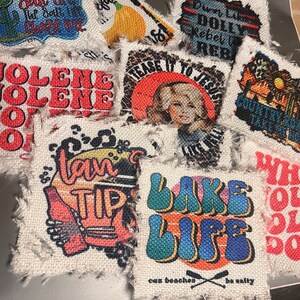 May include: A collection of colorful fabric patches with various designs and text, including "Jolene", "Down Life Dolly Rebel Rebel", "Tease It To Jesus", "Country Strong", "I Can Tip", "Lake Life", and "Who Dat".