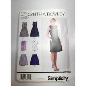 May include: A Simplicity sewing pattern envelope for Cynthia Rowley design 2215, size R5. The front displays illustrations of sleeveless dresses, blouses, and skirts in various colors, alongside a photograph of a grey dress with a collar.