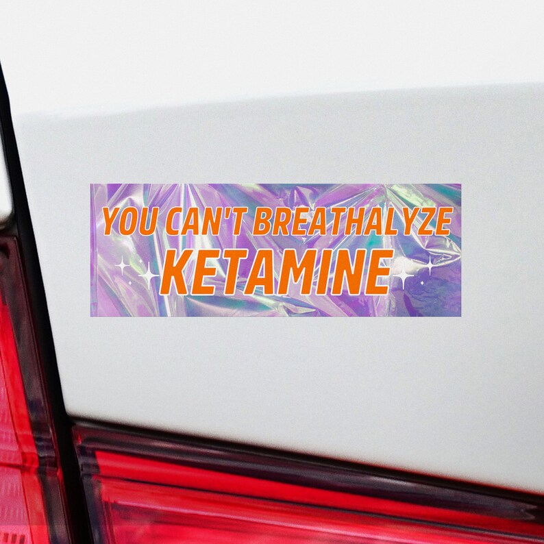 Puede incluir: Una pegatina hologr&aacute;fica con el texto "YOU CAN'T BREATHALYZE KETAMINE" en letras naranjas.