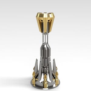 Puede incluir: Objeto decorativo metálico con parte superior e inferior doradas y cuerpo central plateado. El diseño presenta una serie de formas triangulares que apuntan hacia arriba alrededor de la base. La parte superior tiene un diseño geométrico multifacético.