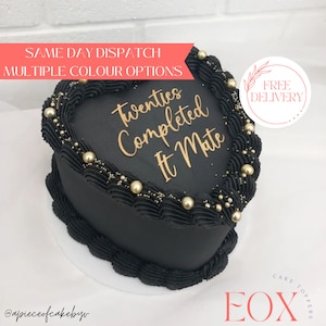 May include: Black heart-shaped cake with gold lettering that says "Twenties Completed It Mate". The cake is decorated with gold sprinkles and pearl-like sprinkles.
