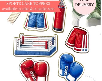 May include: Cake toppers with a boxing theme. The image shows a boxing ring, red and blue boxing gloves, red punching bag, and red and blue boxing shorts. The text reads "Sports Cake Toppers available in cake & cupcake size."