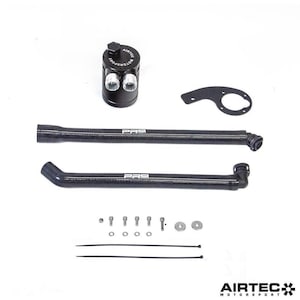 Op de afbeelding: Zwarte olieafscheider met twee inlaten en een zwarte gevlochten slang met een zwarte fitting. De slang is verbonden met een zwarte fitting op de olieafscheider. De olieafscheider is gemarkeerd met "Airtec Motorsport".