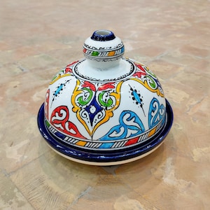 May include: A white ceramic dome with a blue and white base. The dome is decorated with colorful floral patterns in red, yellow, green, and blue.