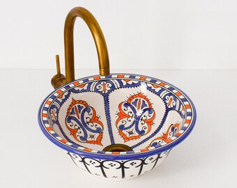 May include: A white ceramic sink with a blue and orange floral pattern. The sink has a brass faucet.