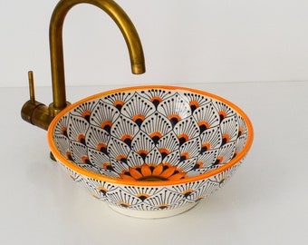 May include: A white ceramic bathroom sink with a blue and orange floral design. The sink has a brass faucet.