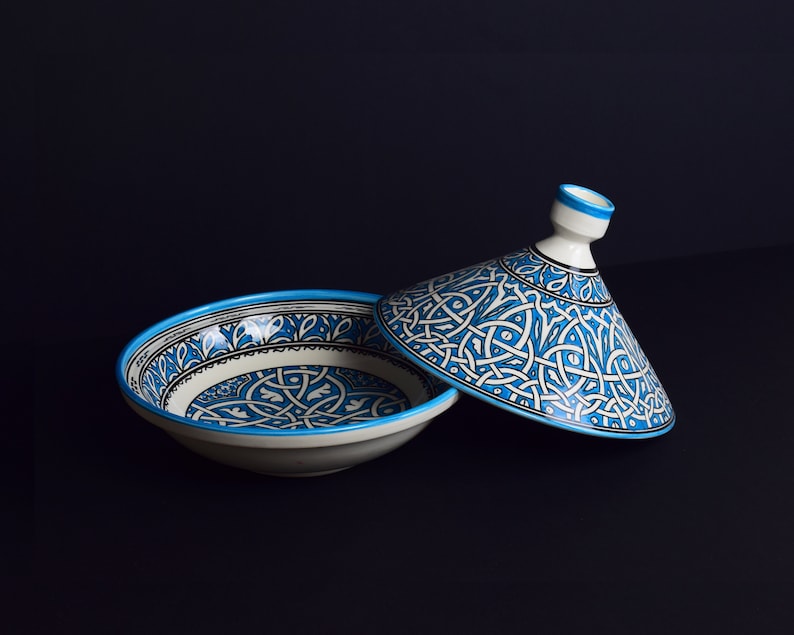 May include: A white ceramic bowl with a blue and white geometric pattern. The bowl has a matching lid with a pointed top.