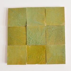 Può includere: Nove piastrelle quadrate in ceramica verde con una glassa screziata. Le piastrelle sono disposte in una griglia 3x3.