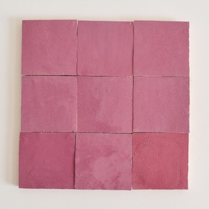 May include: Nine square pink ceramic tiles arranged in a 3x3 grid.