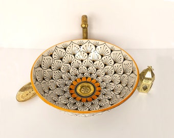 May include: A white ceramic sink with a black and orange floral design. The sink has a brass drain and a brass faucet.