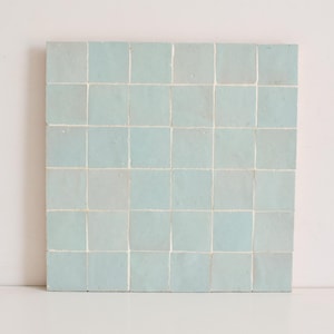 Könnte beinhalten: Eine Fliese aus hellblauem marokkanischem Fliesen mit weißem Fugenmörtel. Die Fliese ist in einem Gittermuster angeordnet.