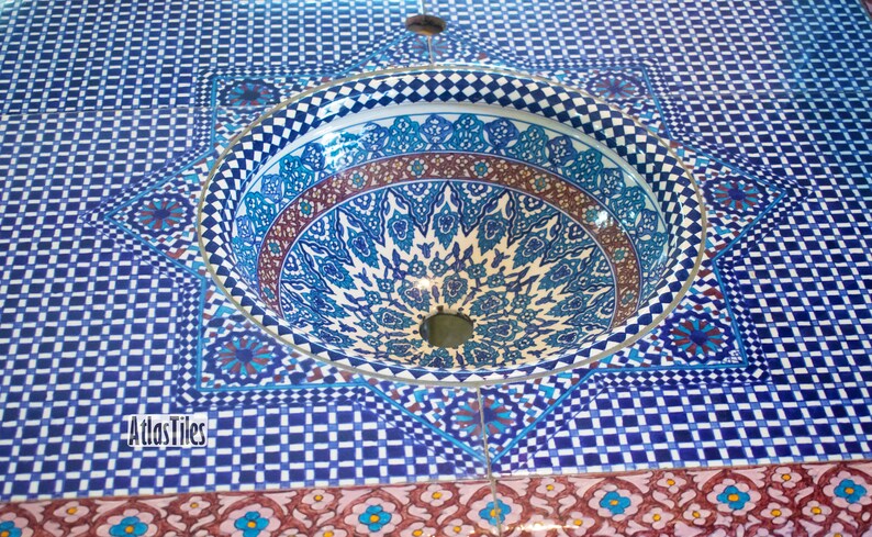 Op de afbeelding: Een blauwe en witte keramische gootsteen met ingewikkelde geometrische patronen. De gootsteen is in een betegelde oppervlakte met een vergelijkbaar patroon geplaatst. De tekst "Atlas Tiles" is zichtbaar in de linkerbenedenhoek van de afbeelding.