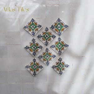 Peut inclure: Neuf carreaux en forme de losange avec un motif floral vert, jaune et bleu sur fond blanc. Les carreaux sont disposés en carré. Le texte "Atlas Tiles" est dans le coin supérieur gauche.