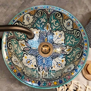 May include: A turquoise ceramic sink with a colorful floral pattern. The sink has a brass drain and is perfect for a bathroom or powder room.
