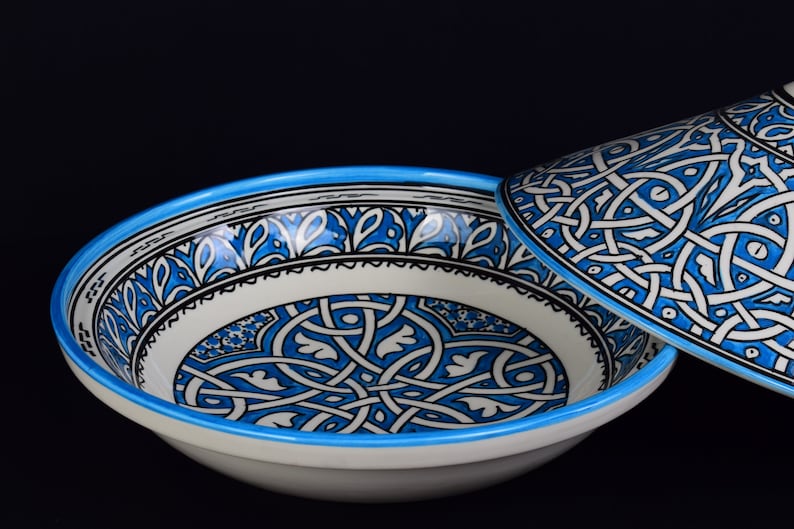May include: A white ceramic bowl with a blue and black geometric pattern. The bowl has a matching lid.