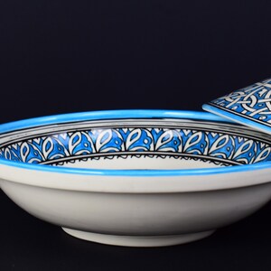 May include: A white ceramic bowl with a blue and black geometric pattern around the rim. The bowl is part of a set and has a matching lid.