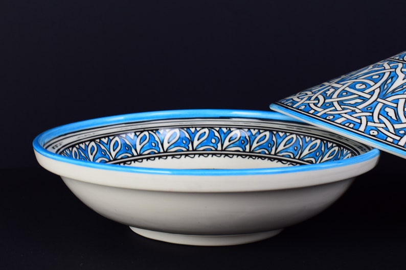May include: A white ceramic bowl with a blue and black geometric pattern around the rim. The bowl is part of a set and has a matching lid.