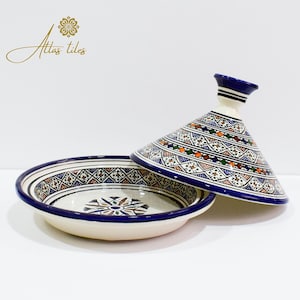 May include: A white ceramic tagine with a blue and orange geometric pattern. The tagine has a round base and a conical lid.