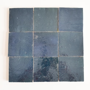 Può includere: Nove piastrelle quadrate in ceramica di colore blu scuro con una leggera variazione di tonalità. Le piastrelle sono disposte in una griglia 3x3.