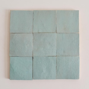 May include: Nine square ceramic tiles in a light blue colour. The tiles are arranged in a 3x3 grid.