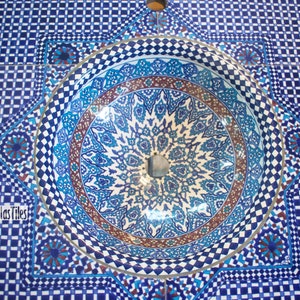 Op de afbeelding: Een blauwe en witte keramische wastafel met ingewikkelde geometrische patronen. De wastafel is in een betegelde oppervlakte met een bijpassend blauw en wit patroon geplaatst.