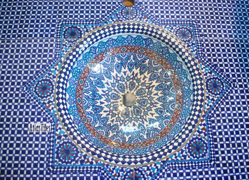 Op de afbeelding: Een blauwe en witte keramische wastafel met ingewikkelde geometrische patronen. De wastafel is in een betegelde oppervlakte met een bijpassend blauw en wit patroon geplaatst.