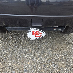K&ouml;nnte beinhalten: Ein rot-wei&szlig;-graues Logo der Kansas City Chiefs an einer schwarzen Anh&auml;ngerkupplung.