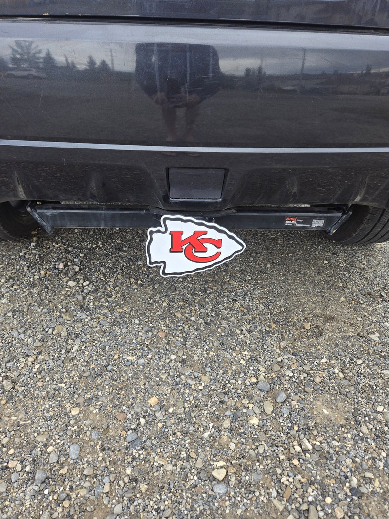 K&ouml;nnte beinhalten: Ein rot-wei&szlig;-graues Logo der Kansas City Chiefs an einer schwarzen Anh&auml;ngerkupplung.