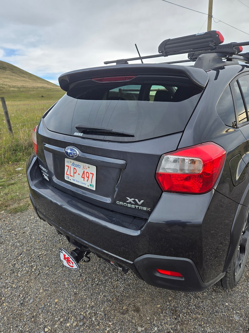 K&ouml;nnte beinhalten: Ein schwarzer Subaru XV Crosstrek mit einem Heckspoiler und einem Nummernschild mit der Aufschrift "ZLP-497". Das Auto hat eine Anh&auml;ngerkupplung mit einem Logo der Kansas City Chiefs.