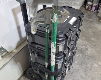 May include: A black tool box with wheels and a handle.  Two green and white poles are secured to the side of the box.  The box has a label that reads "GREENLEE 842".  There are three silver pipe benders on top of the box.