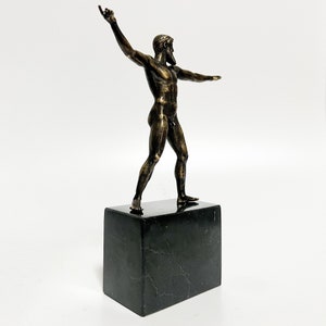 May include: A bronze sculpture of a standing male figure with a beard, on a black marble base.