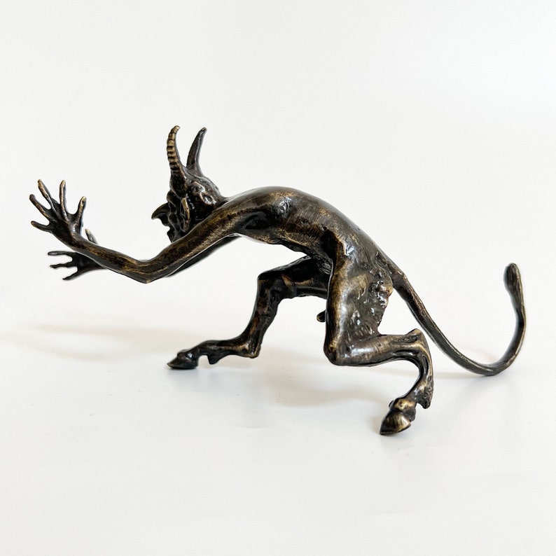 May include: A bronze sculpture of a crouching demon with horns, a long tail, and a clawed hand reaching out.
