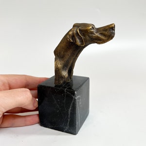 Può includere: Scultura in bronzo di una testa di cane su una base in marmo nero.
