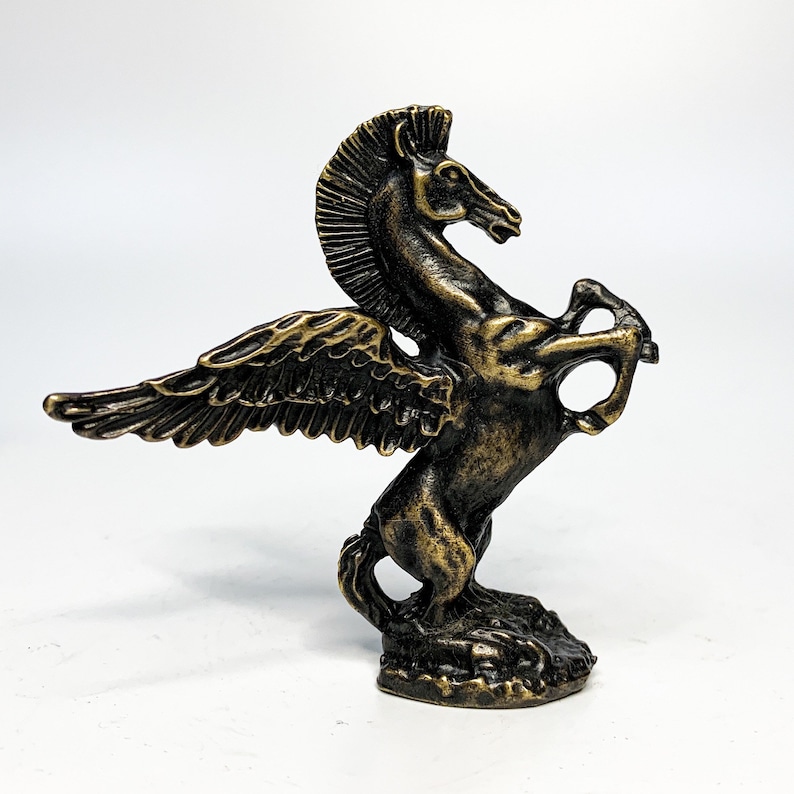 May include: A bronze winged horse statue with a detailed design. The horse is rearing up on its hind legs with its wings spread out. The statue is set on a small base.