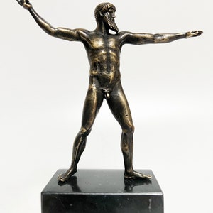 May include: A bronze sculpture of a nude male figure standing with arms outstretched. The sculpture is on a black marble base.